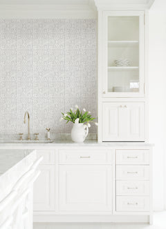 The Ashley Stark Home Willa Tile Peel and Stick Wallpaper by WallPops showcases an ornate, embossed white and light gray tile pattern with symmetrical floral and leaf motifs encircled within each tile. This uniformly repeating design creates a textured, elegant, and vintage look across any surface.