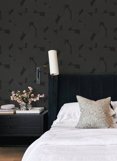 Featuring a pattern of overlapping black geometric shapes—rectangles, semicircles, and squares—set against a dark background, the Ashley Stark Home Bas Geometric Peel and Stick Wallpaper by WallPops creates a subtly textured effect with its nearly indistinguishable monochromatic design.