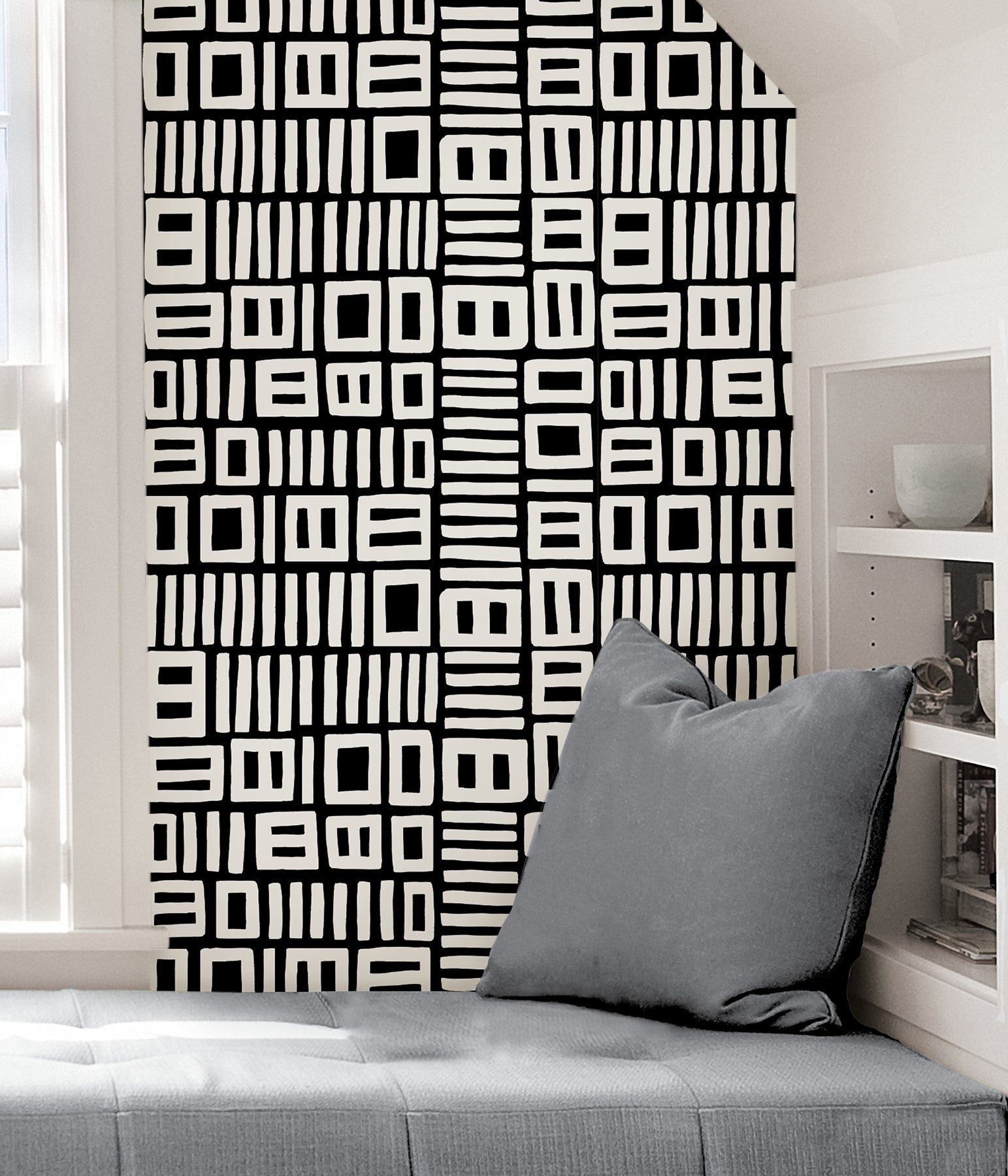 Beneath dark gray cabinets, a backsplash is enhanced with WallPops Black Pepper Paperie Traverse Peel and Stick Wallpaper, showcasing a bold geometric gray and white square pattern reminiscent of striking wallpaper. On the white countertop sit three white canisters with wooden lids alongside a large white bowl filled with green apples.