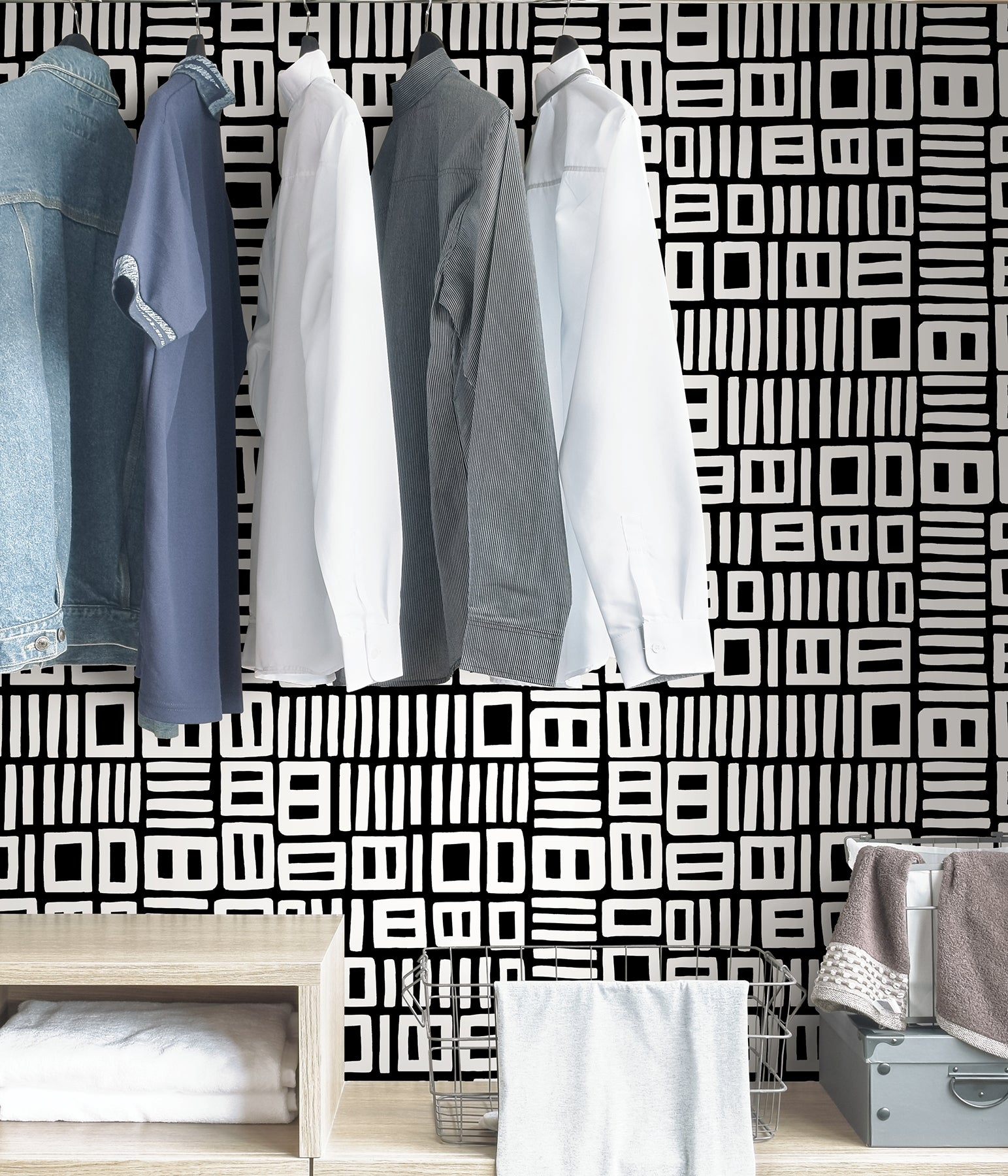 Beneath dark gray cabinets, a backsplash is enhanced with WallPops Black Pepper Paperie Traverse Peel and Stick Wallpaper, showcasing a bold geometric gray and white square pattern reminiscent of striking wallpaper. On the white countertop sit three white canisters with wooden lids alongside a large white bowl filled with green apples.