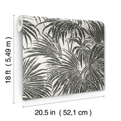 A dense, black and white grunge-style illustration of overlapping cassava palm leaves fills the image, with a light background and distressed textures that give a vintage, weathered appearance—evoking the timeless look of WallPops’ Egypt Sherrod Cassava Palm Peel and Stick Wallpaper. No blank spaces are visible in the pattern.
