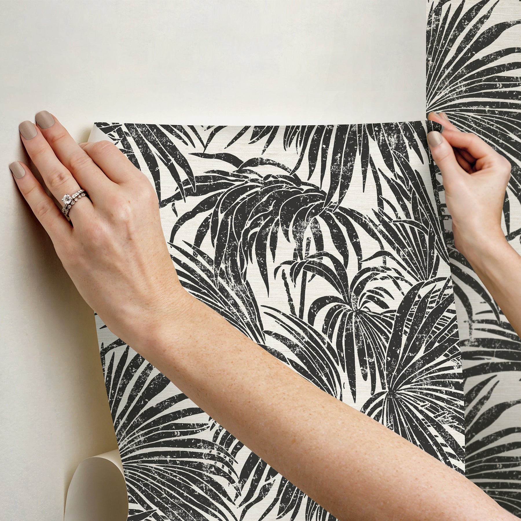 A dense, black and white grunge-style illustration of overlapping cassava palm leaves fills the image, with a light background and distressed textures that give a vintage, weathered appearance—evoking the timeless look of WallPops’ Egypt Sherrod Cassava Palm Peel and Stick Wallpaper. No blank spaces are visible in the pattern.