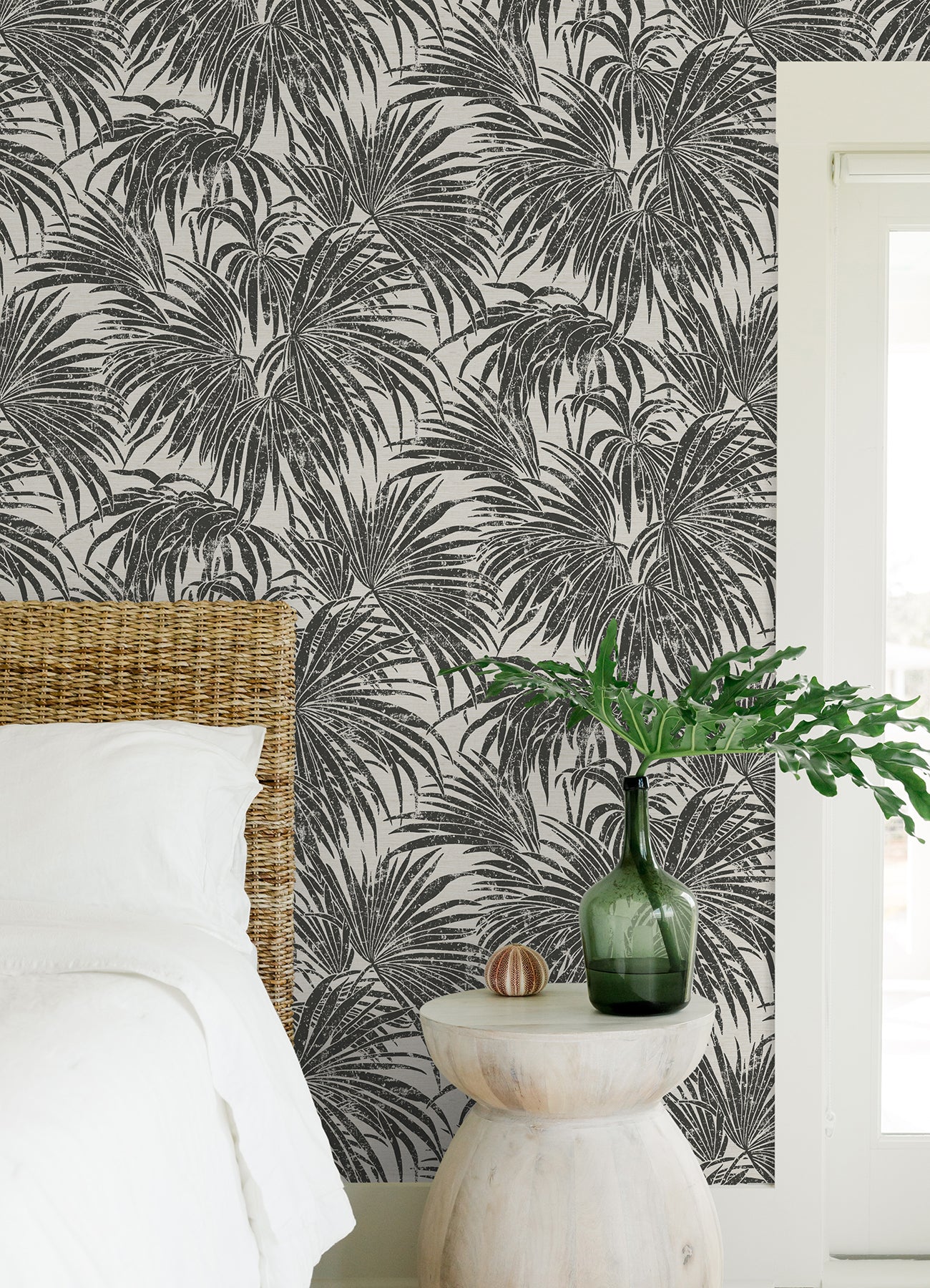 A dense, black and white grunge-style illustration of overlapping cassava palm leaves fills the image, with a light background and distressed textures that give a vintage, weathered appearance—evoking the timeless look of WallPops’ Egypt Sherrod Cassava Palm Peel and Stick Wallpaper. No blank spaces are visible in the pattern.