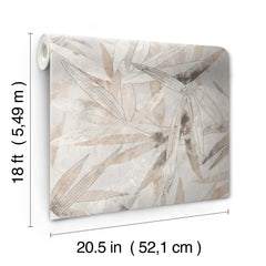 A person peels back a corner of the WallPops Egypt Sherrod Bali Bamboo Peel and Stick Wallpaper, which features abstract leaf designs in beige, gray, and blush tones. The wallpaper is displayed on a wooden surface, and the person wears a wedding ring and another ring on their left hand’s ring finger.