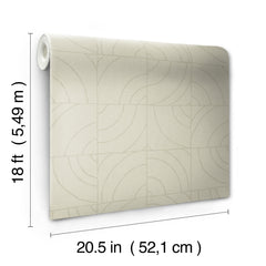 A person’s hands peel back a corner of WallPops Egypt Sherrod Batik Blok Peel and Stick Wallpaper, featuring abstract curved lines on a beige background, revealing its adhesive backing. The wallpaper rests on a wooden surface, and the person wears a ring on their left hand.
