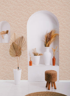 Two hands peel back a sheet of WallPops Egypt Sherrod Ridge & Valley Peel and Stick Wallpaper, which features a white abstract geometric line pattern on a beige background. The wallpaper is partially lifted from a wooden surface, and the person’s left hand is adorned with a ring.