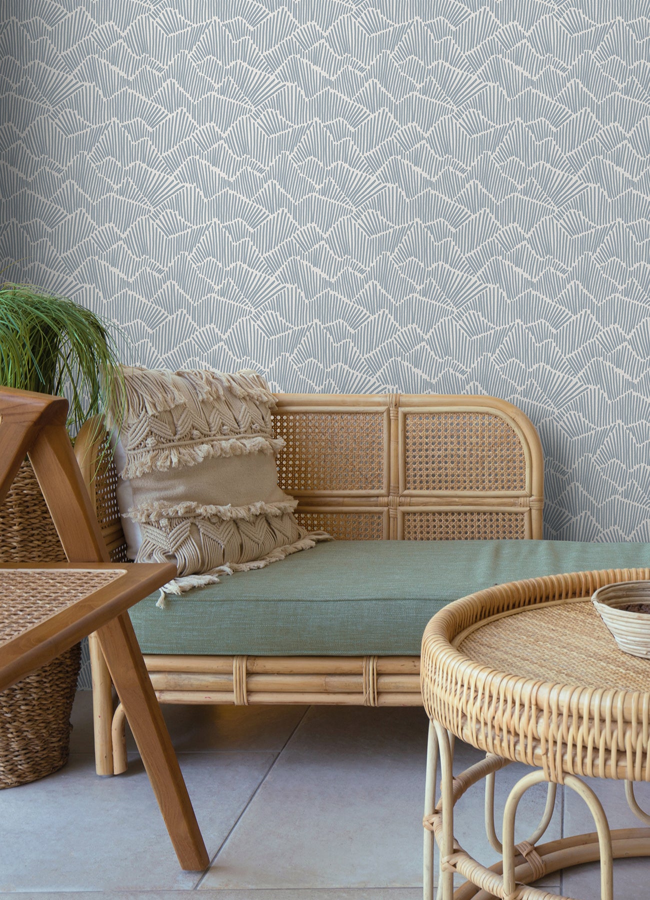 Two hands peel back a sheet of WallPops Egypt Sherrod Ridge & Valley Peel and Stick Wallpaper, which features a white abstract geometric line pattern on a beige background. The wallpaper is partially lifted from a wooden surface, and the person’s left hand is adorned with a ring.