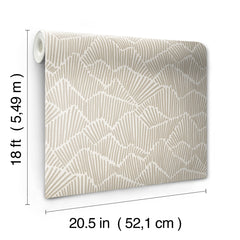 Two hands peel back a sheet of WallPops Egypt Sherrod Ridge & Valley Peel and Stick Wallpaper, which features a white abstract geometric line pattern on a beige background. The wallpaper is partially lifted from a wooden surface, and the person’s left hand is adorned with a ring.
