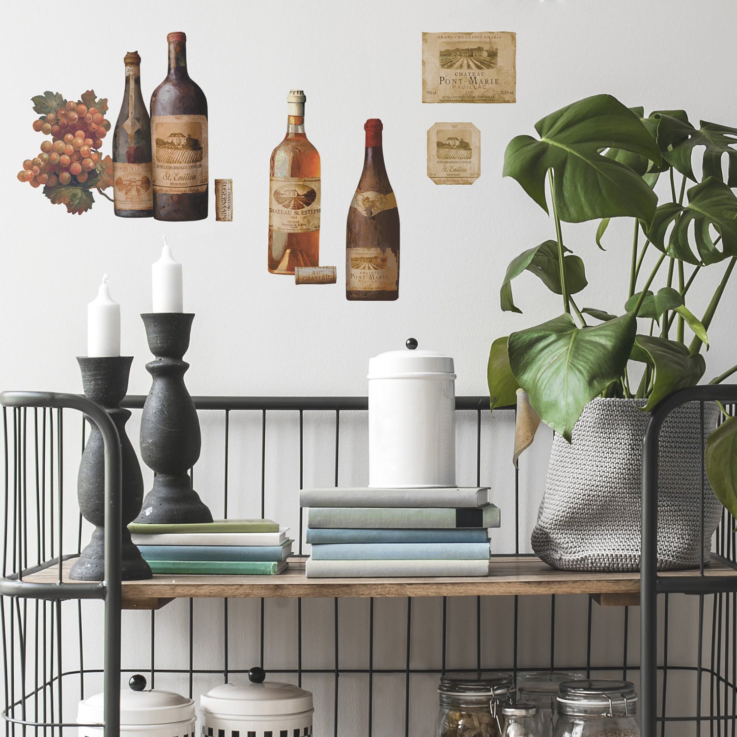 WallPops Wine Tasting Wall Decals package comes with 56 charming peel and stick decals featuring a delightful wine and kitchen motif. The sample image shows bottles, jars, and glasses arranged artfully on a kitchen counter, making them a perfect match for rustic interiors. These easy-to-apply wall decals are visible through the packaging window, offering an ideal way to bring countryside charm to your space.