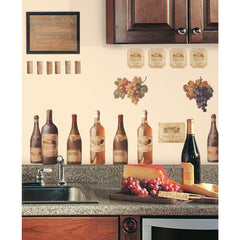 WallPops Wine Tasting Wall Decals package comes with 56 charming peel and stick decals featuring a delightful wine and kitchen motif. The sample image shows bottles, jars, and glasses arranged artfully on a kitchen counter, making them a perfect match for rustic interiors. These easy-to-apply wall decals are visible through the packaging window, offering an ideal way to bring countryside charm to your space.