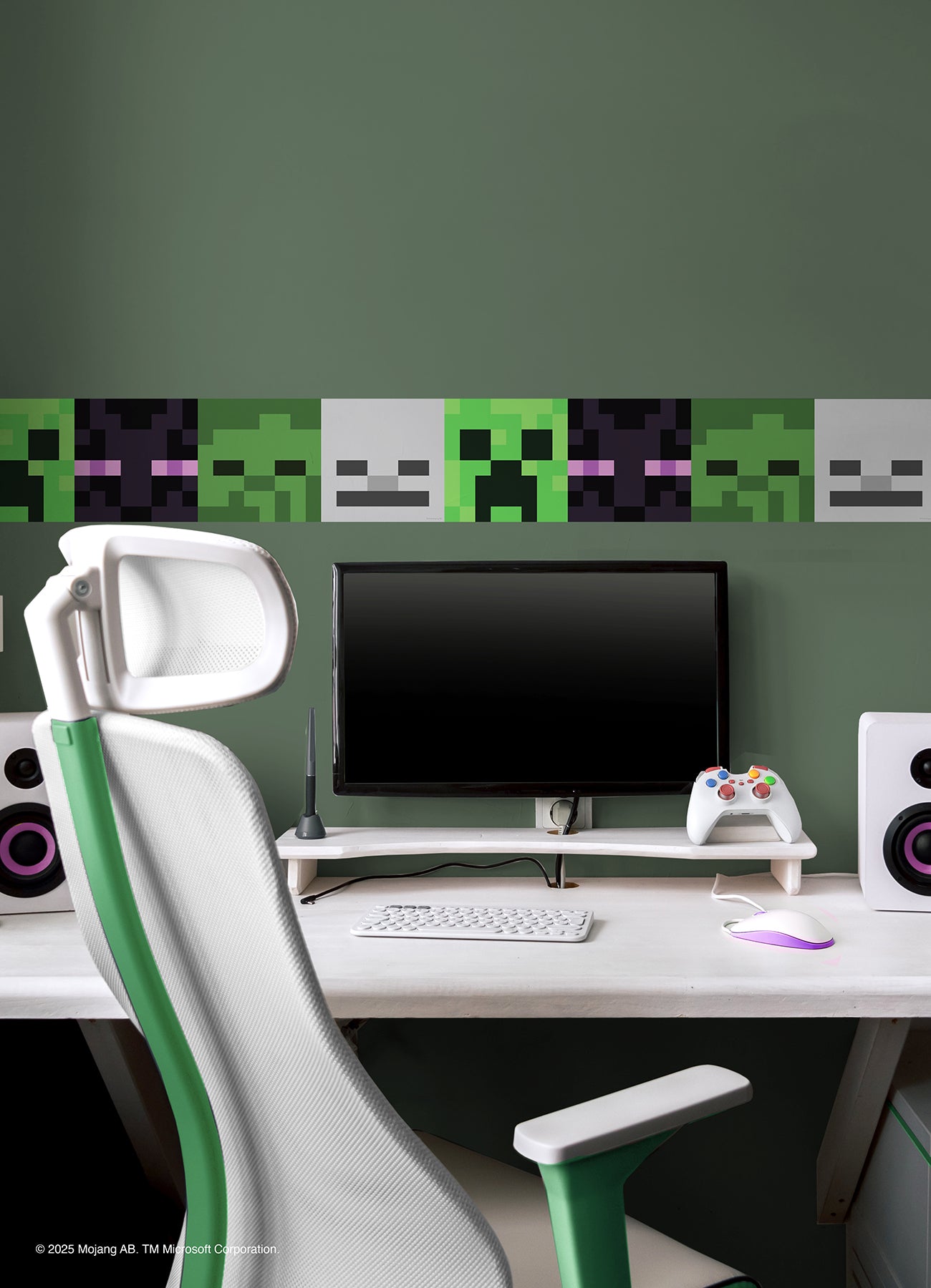 A modern gaming setup features a white desk, keyboard, mouse, monitor, speakers, controller, and a green wall decorated with Minecraft Hostile Mobs Wall Decals showing pixel art creepers and skeletons.