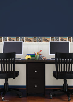 A white decorative rocket stands on a wooden shelf beside white books. Below are two beige storage bins. Behind, a light blue wall features a border of whimsical Star Wars The Mandalorian and Grogu linocut illustrations created with WallPops peel and stick wall decals. The scene is neatly arranged and playful.