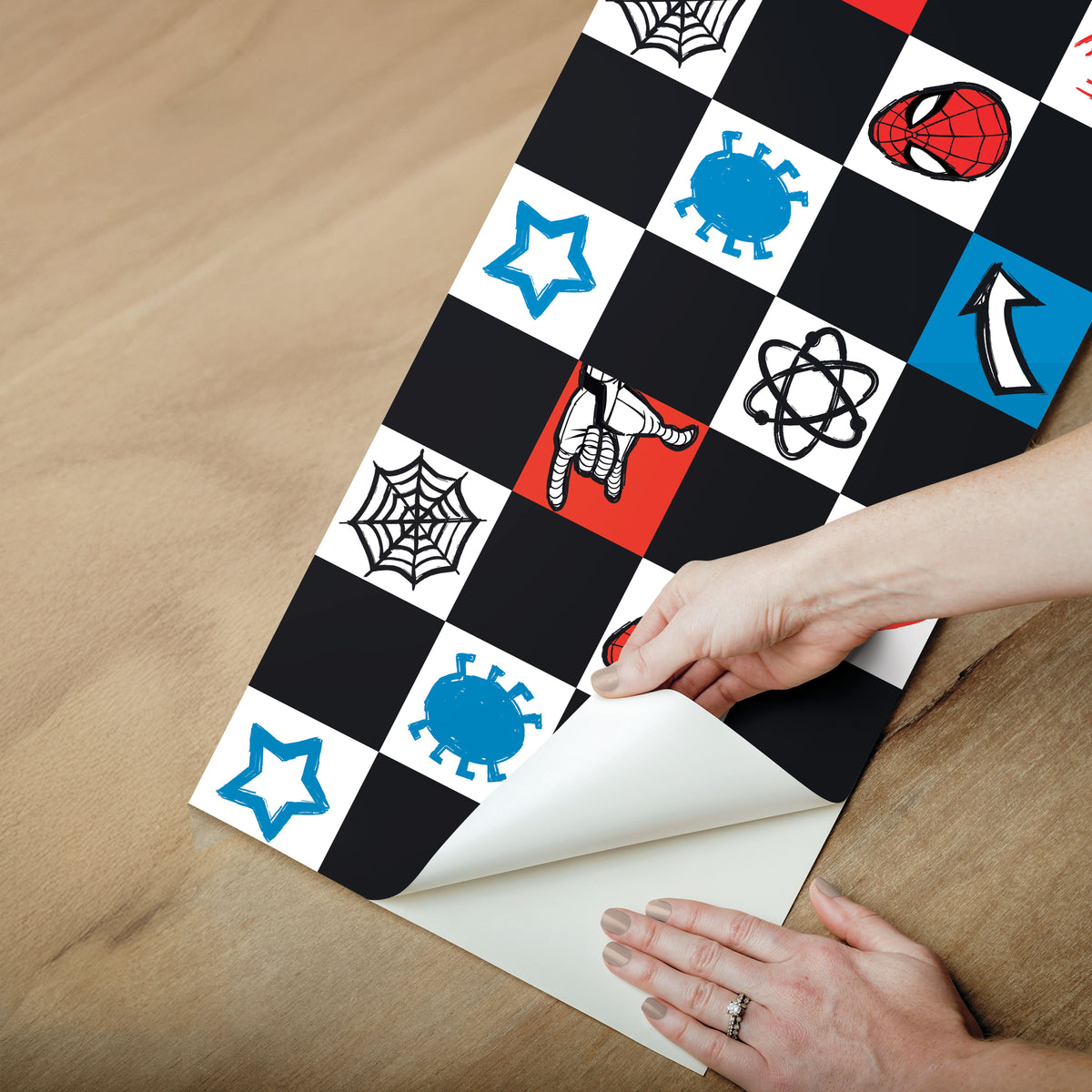 Spider-Man Checker Borders by WallPops features a dynamic checkerboard pattern with Spider-Man heads, red spiders, blue virus icons, comic-style arrows, white stars, web-shooting hands, black atom symbols, and webs across bold black, white, blue, and red squares. Inspired by rustic elements and distressed barn wood textures for enhanced character and style, this eye-catching peel-and-stick border brings a pop-art vibe to any space.