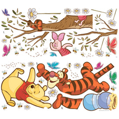 Winnie the Pooh dangles from Tigger’s tail, reaching for a falling honey pot, while Tigger hangs upside down from a tree branch as Piglet looks on above. Blue and red butterflies flutter nearby, and daisies grow below, creating a cheerful scene. The Disney Winnie the Pooh Swinging for Honey Giant Wall Decals by WallPops features these charming characters with rustic design elements—perfect for peel and stick wall decals or as accents on distressed barn wood décor to bring warmth to any room.