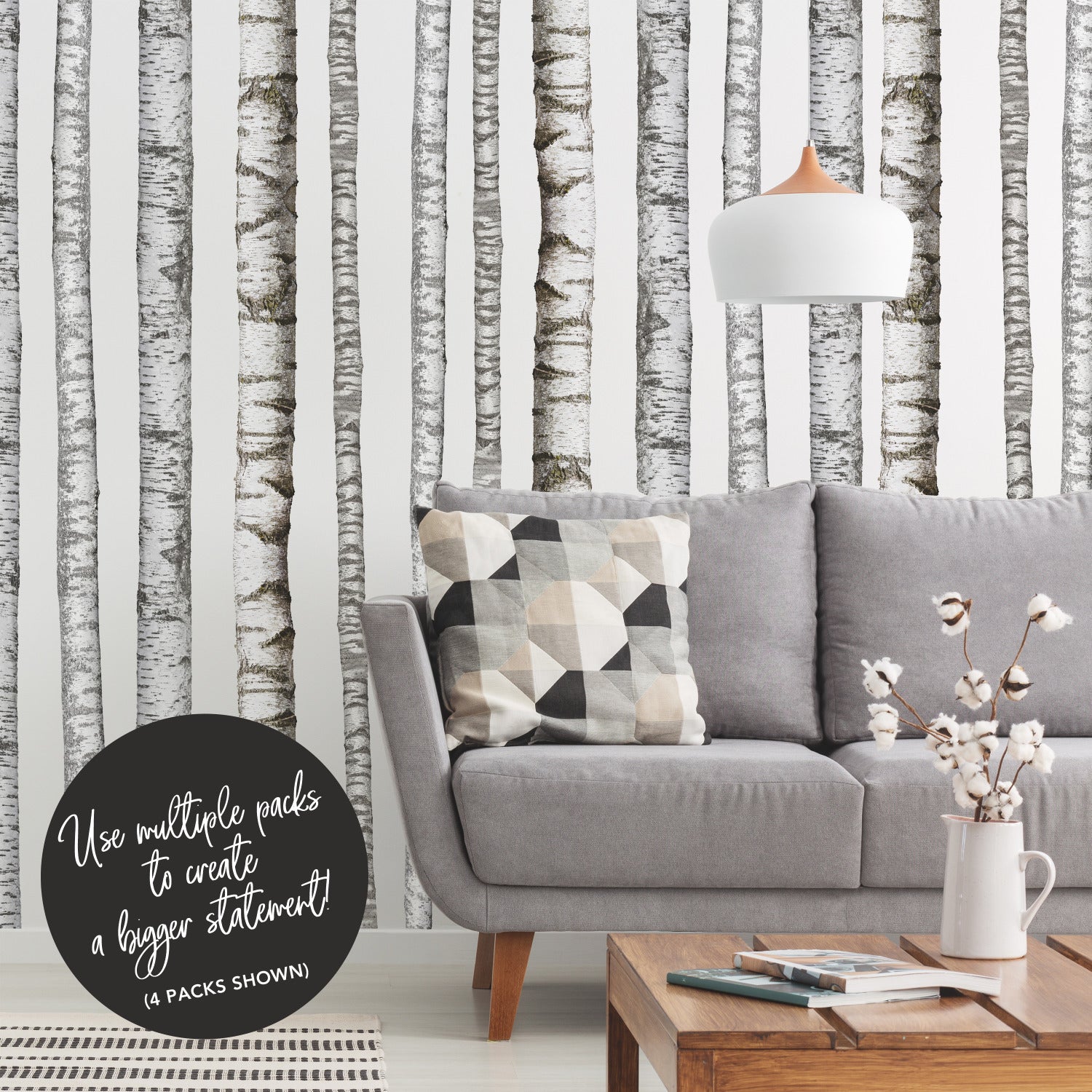 A modern bedroom features a wooden bed with crisp white bedding, a plush fur throw, potted plants, a wooden side table, and open shelving displaying both décor and additional greenery. The pale walls are adorned with the Realistic Birch Trees Peel and Stick Giant Wall Decals by WallPops, creating a serene birch tree mural that enhances the room’s natural ambiance. Subtle accents of distressed barn wood infuse rustic charm into this bright and minimal space.