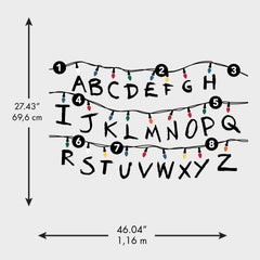 The WallPops Netflix Stranger Things Christmas Lights Peel And Stick Giant Wall Decals With Alphabet features a hand-drawn alphabet arranged in three rows, each row displayed beneath a line of colorful Christmas lights and accented with circled numbers 1–8 along the lines. This rustic design, measuring 27.43 69.6 cm tall by 46.04 1.16 m wide, boasts a light gray background reminiscent of distressed barn wood for added character.