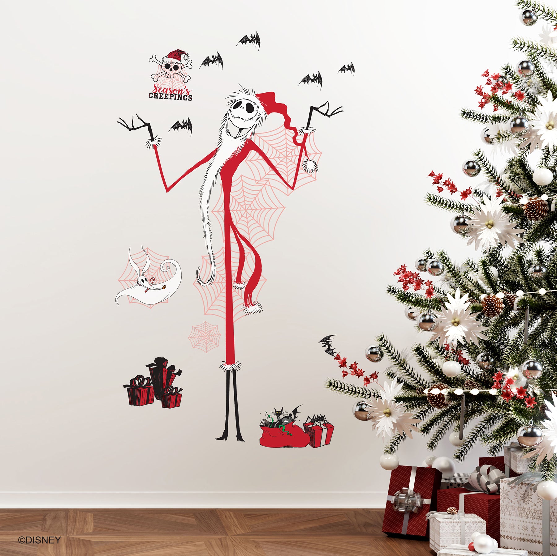 Giant Disney Tim Burtons The Nightmare Before Christmas Holiday Wall Decals by WallPops, featuring Jack Skellington, Zero, bats, spider webs, skulls, and presents, decorate the living room wall above a couch adorned with tree pillows. Rustic barn wood accents enhance the festive scene, while wrapped gifts, a lantern, and a blanket on the floor create a cozy blend of Halloween and Christmas décor.