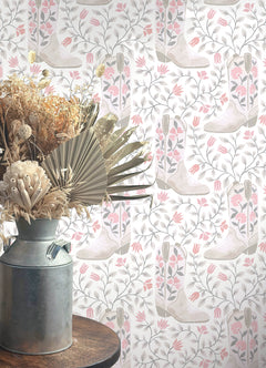 Introducing the Cowgirl Like Me Peel and Stick Wallpaper by WallPops—this seamless wallpaper showcases pale beige cowboy boots accented with delicate floral motifs, all arranged against a light backdrop interwoven with winding leafy vines and dainty blossoms. The soft, muted illustration style lends a subtle vintage charm, making it the ideal choice for anyone seeking adorable cowgirl-inspired décor.