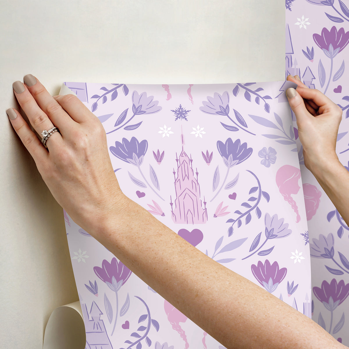 WallPops Frozen II Frozen Castle Damask Peel and Stick Wallpaper features pastel pink and lavender castle motifs with floral patterns, stylized flowers, leaves, hearts, and face profiles. Removable. Dimensions: 18 ft x 20.5 in.