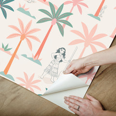 Two twin beds with white bedding flank a white nightstand, which holds a lamp, plant, and books. The WallPops Disney Moana Coconut Tree Peel and Stick Wallpaper showcases green and pink palm trees mixed with small black-and-white illustrations of women, bringing an artistic flair to the space. The overall look is fresh, playful, and tropical.