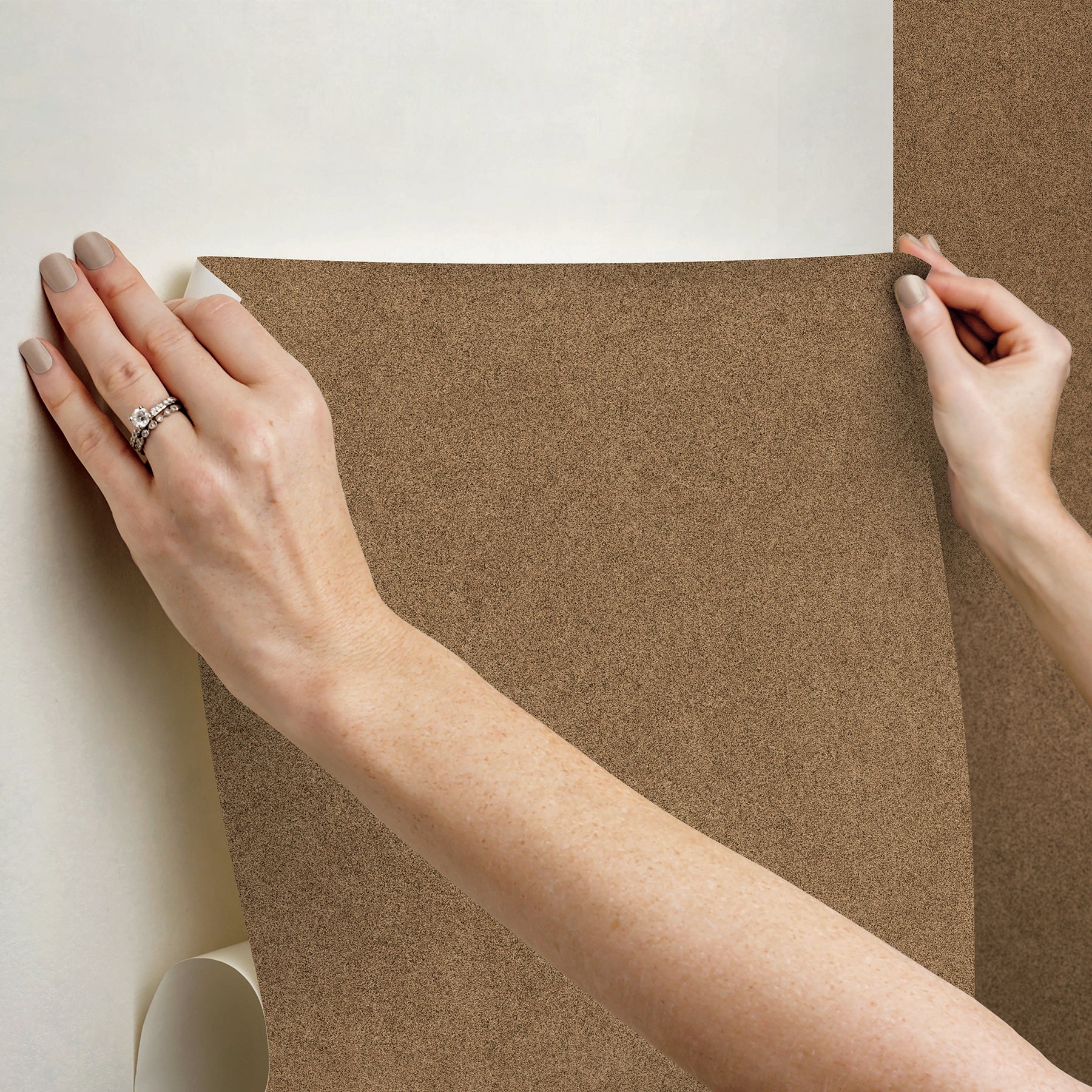A close-up view of a cork board surface reveals a natural, subtly uneven texture composed of tiny light to medium brown granules pressed together. This organic look would beautifully complement WallPops’ RuPaul RuSuede Peel and Stick Wallpaper or pair seamlessly with other azure blue wallcoverings for easy and stylish customization. The surface is shown free from any objects, pins, or text.