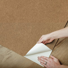 A close-up view of a cork board surface reveals a natural, subtly uneven texture composed of tiny light to medium brown granules pressed together. This organic look would beautifully complement WallPops’ RuPaul RuSuede Peel and Stick Wallpaper or pair seamlessly with other azure blue wallcoverings for easy and stylish customization. The surface is shown free from any objects, pins, or text.